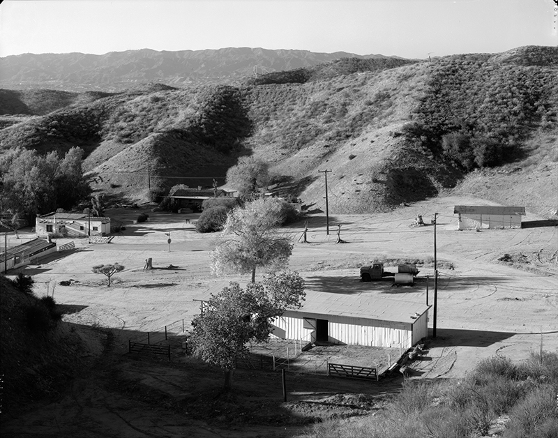 GENERAL VIEW OF WOOD STABLES (FRONT CENTER), WITH POOL CABANA, JOE'S CABIN, BUNKHOUSE, AND ADOBE STABLE TO REAR, LEFT TO RIGHT; CAMERA FACING SOUTH